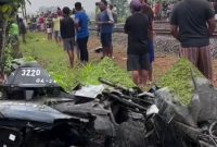 Motor korban nampak remuk, sementara warga berkumpul di lokasi kejadian.