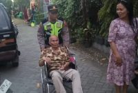 AKP Sugiman SH, saat mengantar seorang kakek pergi ke gereja, dengan mendorong kursi roda.