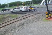 Nampak Kabid Humas Polda Jateng, bersama warga mendorong mobil mogok di perlintasan kereta api.