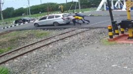 Nampak Kabid Humas Polda Jateng, bersama warga mendorong mobil mogok di perlintasan kereta api.