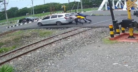 Nampak Kabid Humas Polda Jateng, bersama warga mendorong mobil mogok di perlintasan kereta api.