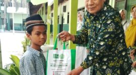 Kepala MTs NU Raudlotus Shibnyan, Abdul Manan, saat memberikan paket bantuan sembako kepada anak kurang mampu.