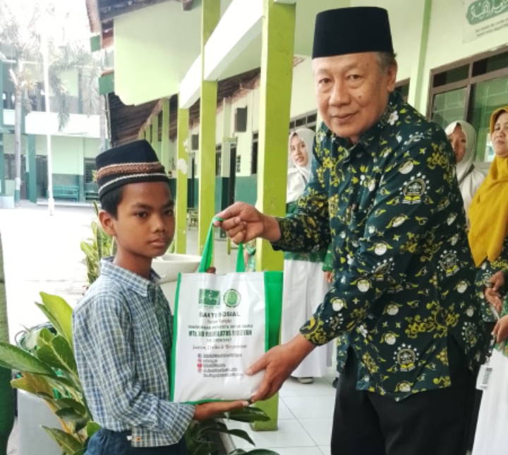 Kepala MTs NU Raudlotus Shibnyan, Abdul Manan, saat memberikan paket bantuan sembako kepada anak kurang mampu.