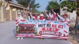 Peserta jalan sehat warga sambirejo RT 01 RW 04, saat melintasi jalan raya disamping Masjid Muttaqin Sambirejo. Minggu (16/8/2026).