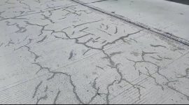 Foto: Kondisi proyek jalan beton nampak retak-retak hitam tambalan aspal.