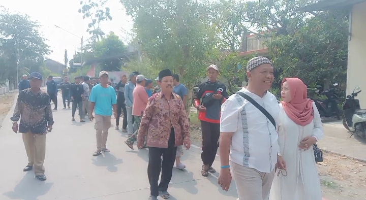 Foto: H. Moh. Asrori, didampingi istri (Nurkhasanah) bersama ratusan warga pendukung, berjalan kaki menuju kantor sekretariat panitia Pilkades, untuk mendaftar bakal calon kades Putatnganten. Senin (12/10/2026).